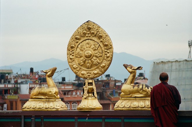 Description: Vị Lama (tăng sĩ theo truyền thống Phật giáo Tây Tạng) đứng trên tầng cao nhất của một tu viện ở Kathmandu (Nepal). Hình ảnh hai chú nai hướng về bánh xe pháp luân là biểu tượng phổ biến ở các tu viện theo truyền thống Phật giáo Tây Tạng.